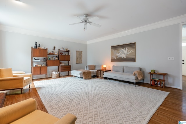 living room with a ceiling fan, crown molding, baseboards, and wood finished floors