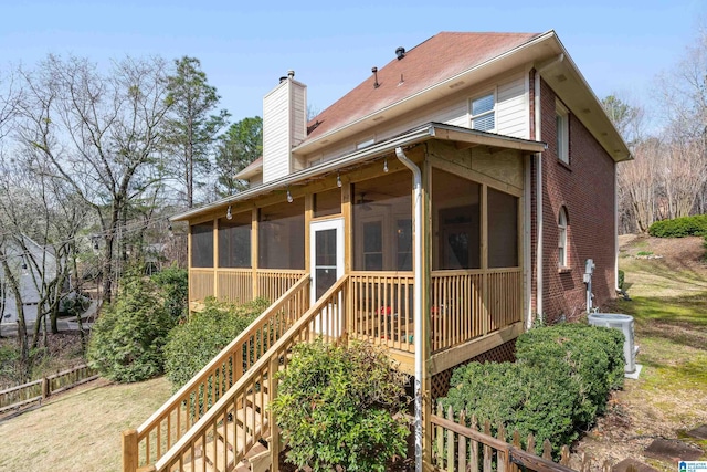 back of property with central AC, stairway, a sunroom, brick siding, and a chimney