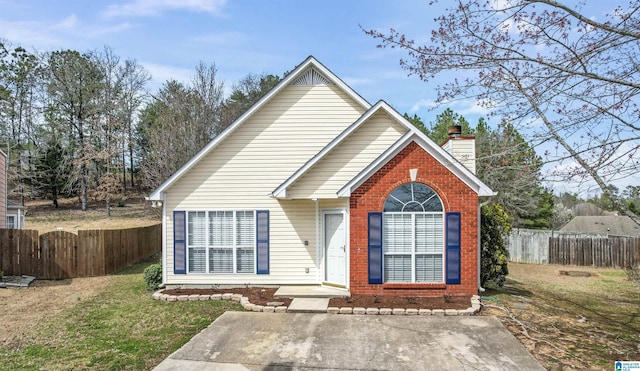 traditional-style home featuring a front yard, brick siding, a chimney, and fence