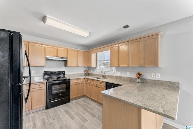 kitchen featuring light brown cabinets, a peninsula, a sink, black appliances, and under cabinet range hood