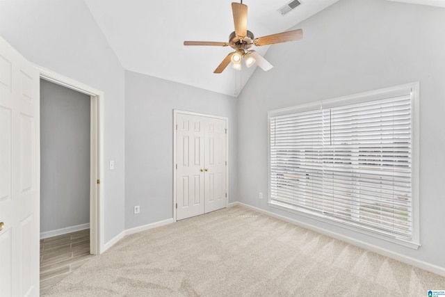 unfurnished bedroom featuring visible vents, a closet, carpet flooring, baseboards, and vaulted ceiling