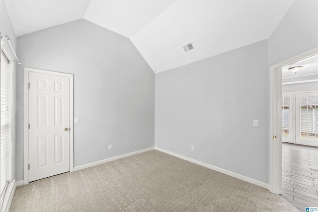 interior space featuring visible vents, carpet floors, baseboards, and vaulted ceiling