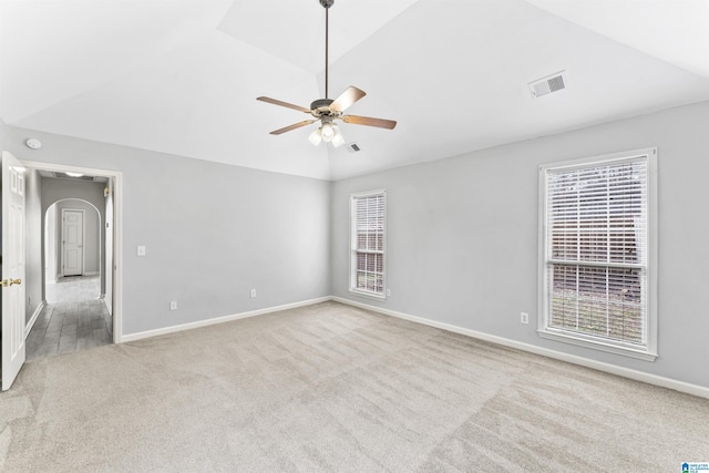 carpeted spare room with visible vents, baseboards, ceiling fan, and vaulted ceiling