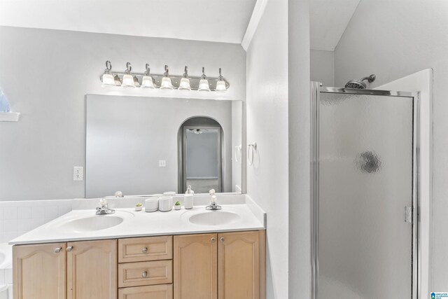 bathroom with a sink, a stall shower, and double vanity