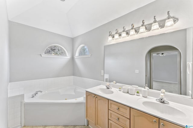 full bath with a sink, lofted ceiling, double vanity, and a whirlpool tub