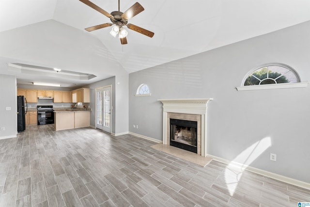 unfurnished living room featuring a ceiling fan, a fireplace, baseboards, and light wood finished floors