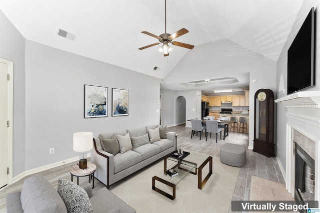 living room with visible vents, arched walkways, a fireplace, baseboards, and wood tiled floor