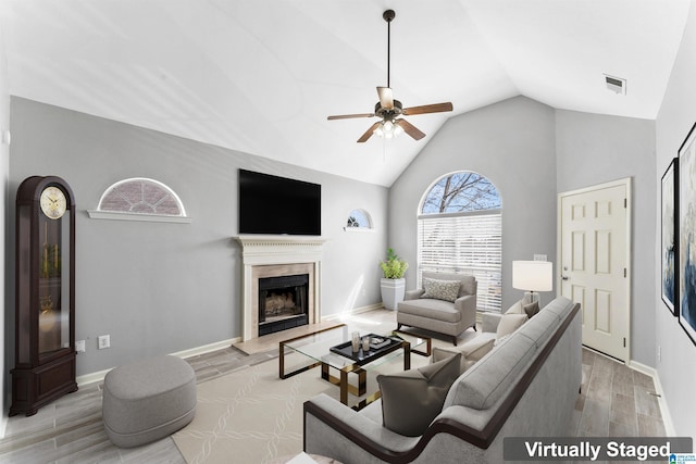 living room featuring visible vents, ceiling fan, baseboards, wood tiled floor, and a premium fireplace