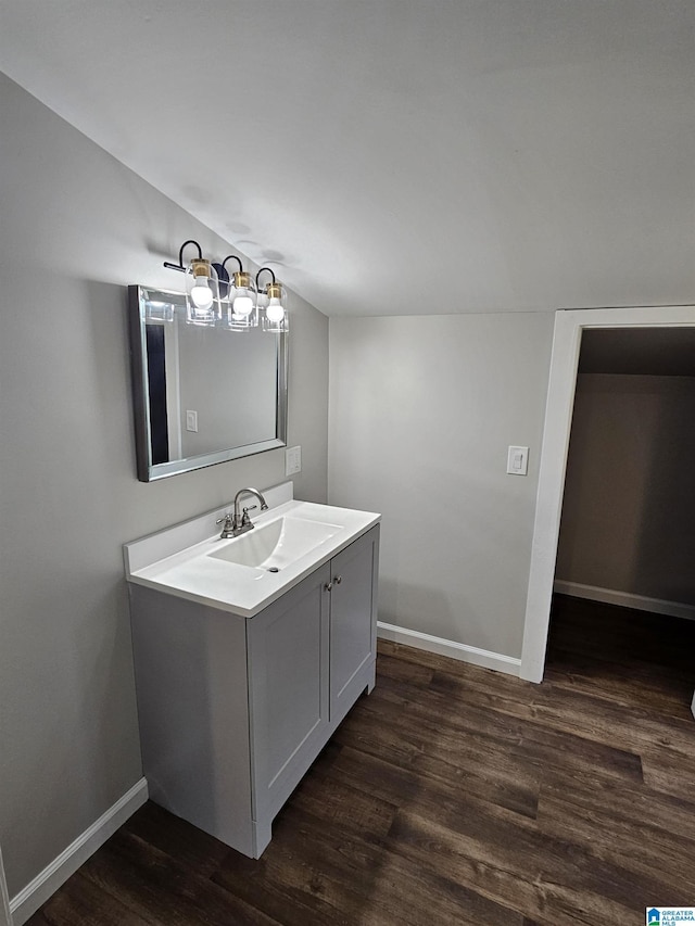 bathroom with vaulted ceiling, vanity, baseboards, and wood finished floors