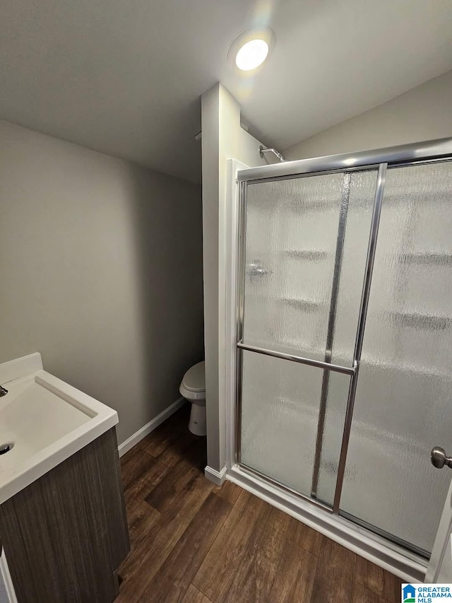 bathroom featuring a shower stall, toilet, baseboards, and wood finished floors