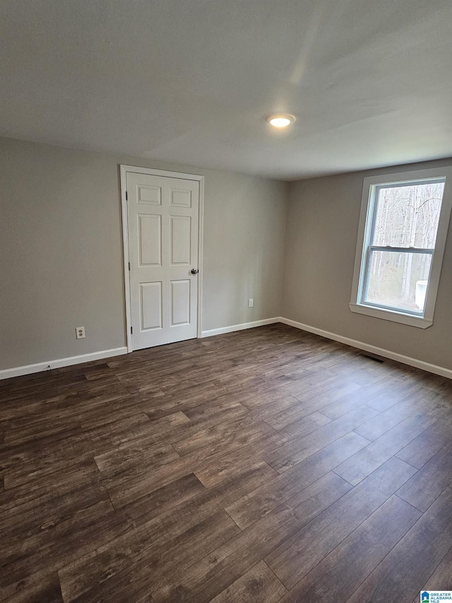 spare room with visible vents, baseboards, and dark wood finished floors