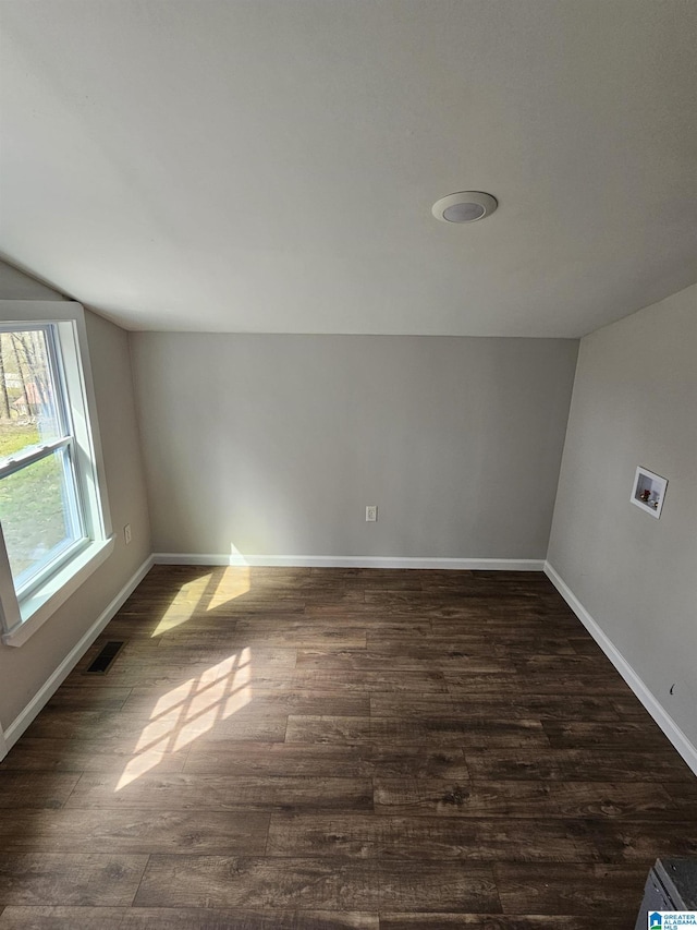 spare room with visible vents, baseboards, and dark wood-style floors