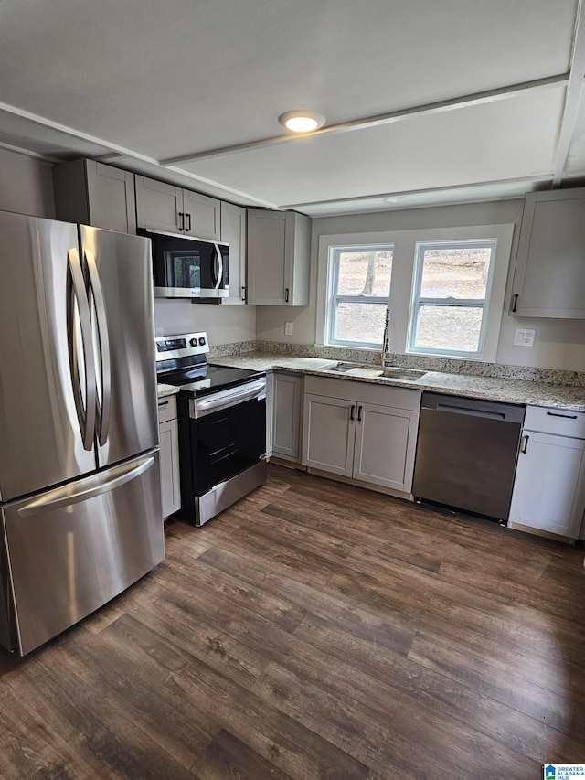 kitchen with a sink, gray cabinetry, dark wood finished floors, and stainless steel appliances