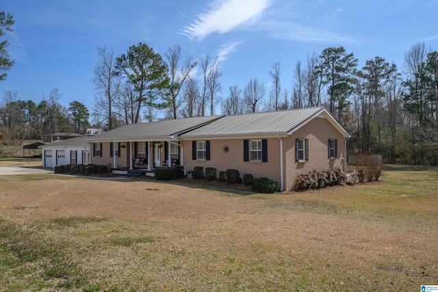 ranch-style house with brick siding, a front lawn, covered porch, metal roof, and an attached garage