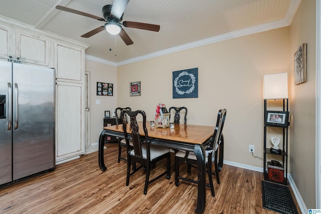 dining room featuring baseboards, a ceiling fan, wood finished floors, and crown molding