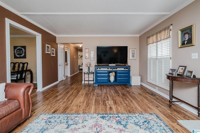 living area with wood finished floors, baseboards, and ornamental molding