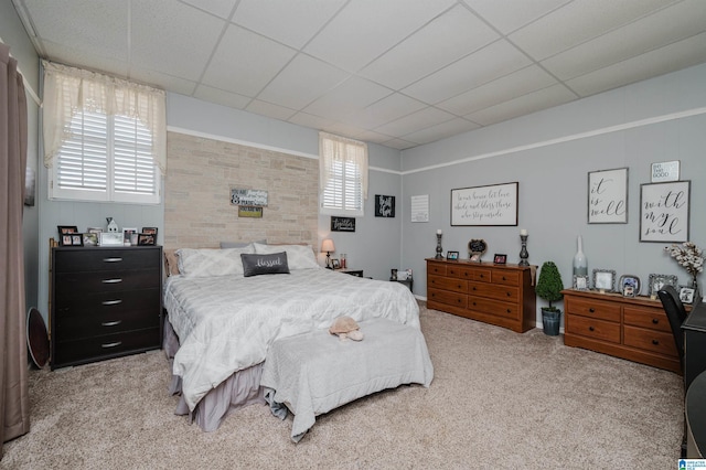 bedroom with multiple windows, a paneled ceiling, and light carpet