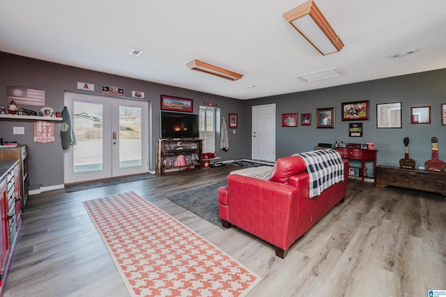 living area with wood finished floors, visible vents, french doors, and baseboards