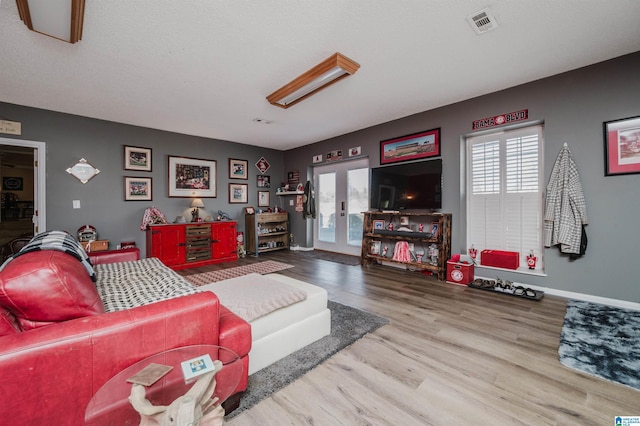 living area featuring visible vents, french doors, baseboards, and wood finished floors