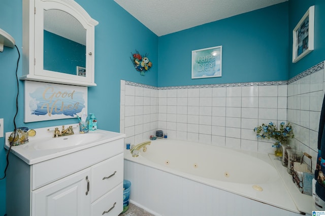 full bath with a whirlpool tub, vanity, and a textured ceiling