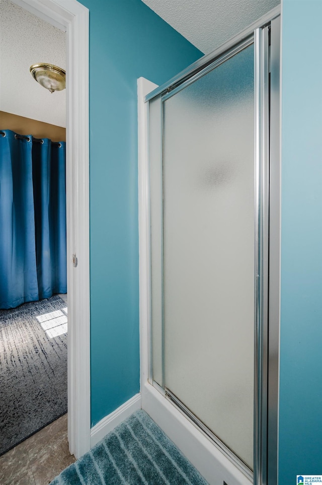 bathroom with a shower with door, a textured ceiling, and baseboards