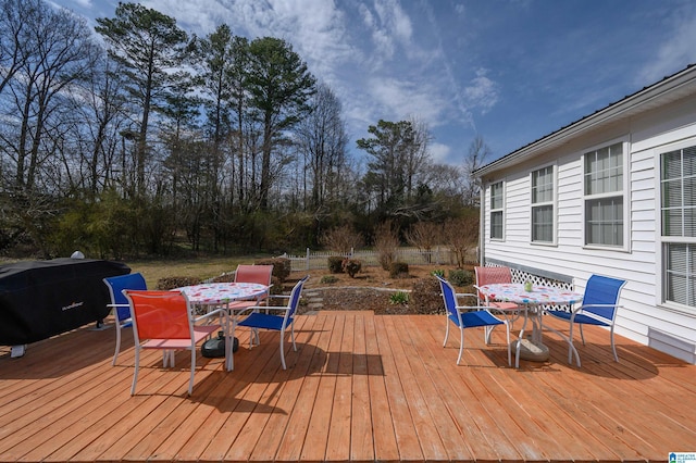 wooden terrace with outdoor dining space and a grill