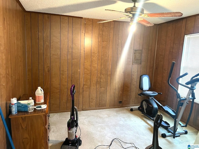 exercise area with baseboards, carpet, wood walls, and a ceiling fan