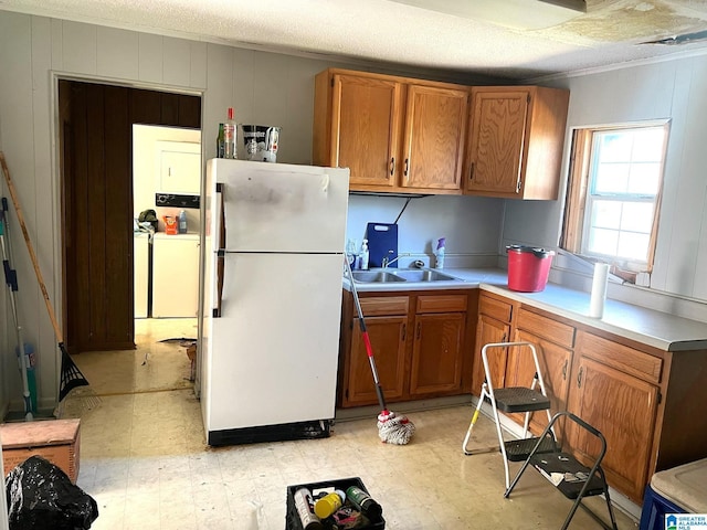 kitchen with a sink, washer / clothes dryer, light floors, and freestanding refrigerator