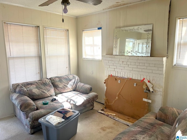 living room featuring carpet flooring, a textured ceiling, crown molding, and a ceiling fan