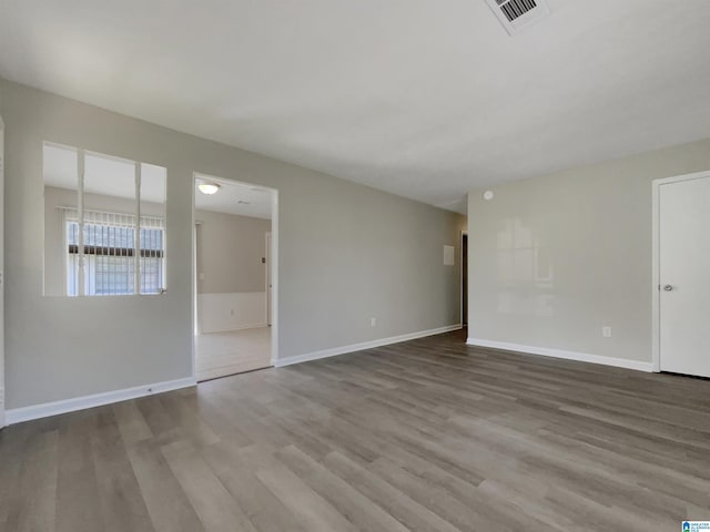 unfurnished room with visible vents, baseboards, and wood finished floors