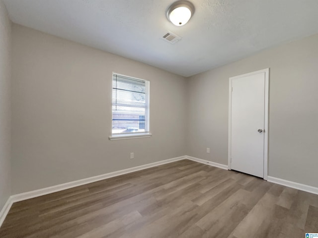 unfurnished room with visible vents, wood finished floors, and baseboards