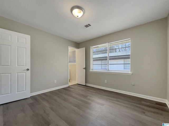 unfurnished bedroom featuring visible vents, baseboards, and dark wood-style flooring