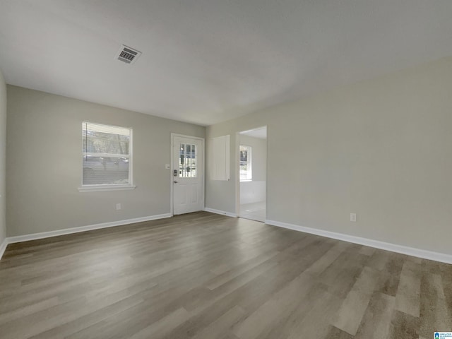 unfurnished room with wood finished floors, visible vents, and baseboards