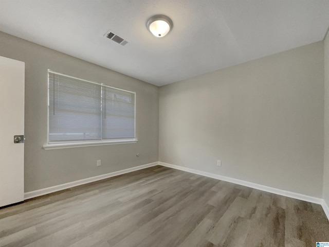 spare room with visible vents, baseboards, and wood finished floors