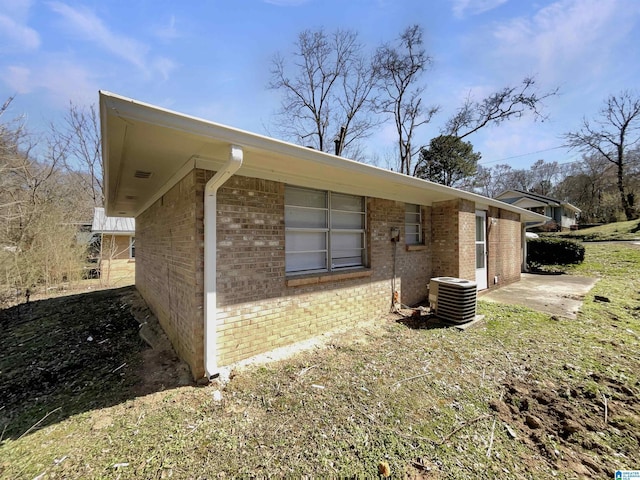 view of side of home featuring brick siding, cooling unit, and a patio