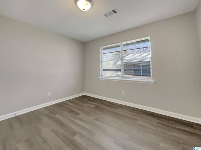 empty room featuring wood finished floors, baseboards, and visible vents