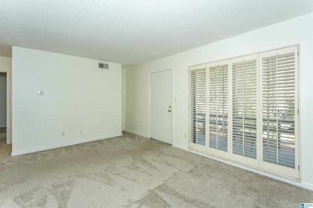 empty room featuring visible vents, baseboards, carpet, and a textured ceiling