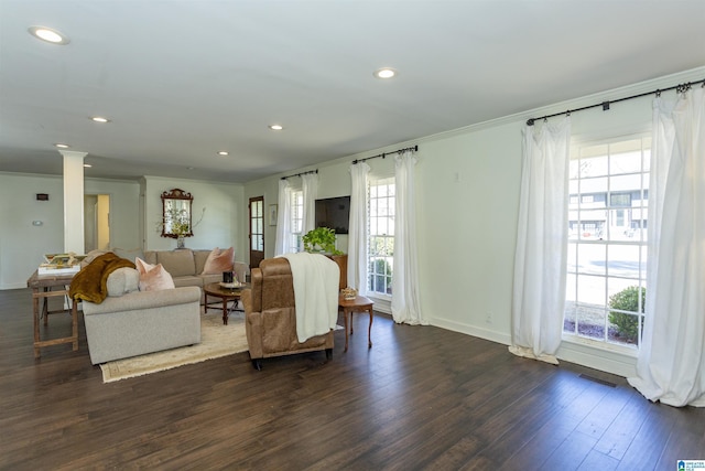 living area featuring visible vents, dark wood-type flooring, crown molding, and decorative columns