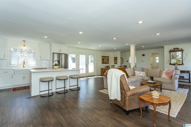 living room featuring decorative columns, a healthy amount of sunlight, dark wood-style floors, and crown molding