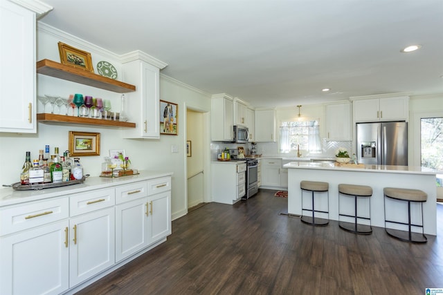 kitchen with dark wood-type flooring, white cabinets, a kitchen breakfast bar, and appliances with stainless steel finishes