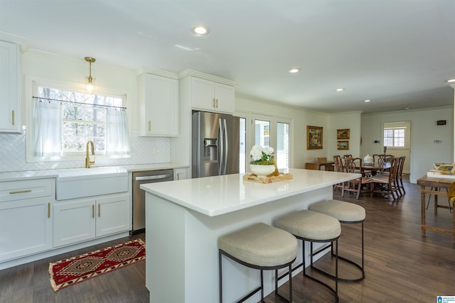 kitchen with a sink, a kitchen breakfast bar, dark wood-style floors, and stainless steel appliances