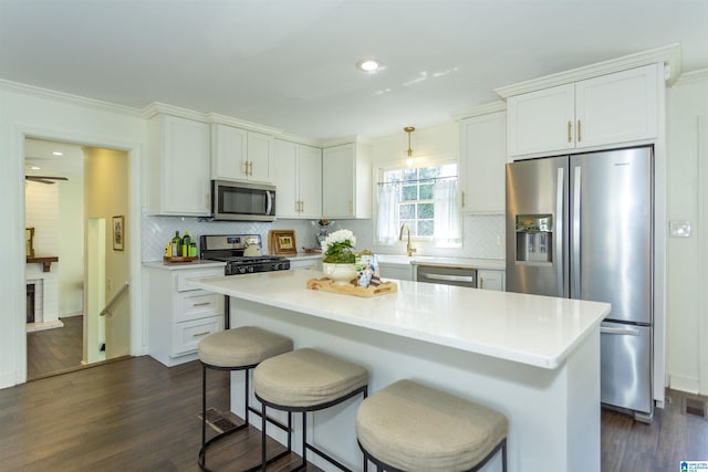 kitchen with dark wood finished floors, appliances with stainless steel finishes, a breakfast bar area, light countertops, and decorative backsplash