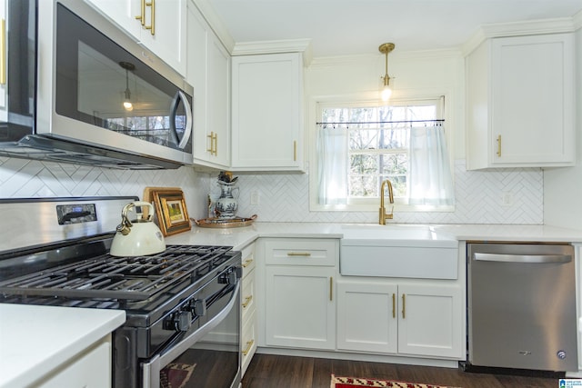 kitchen with a sink, light countertops, appliances with stainless steel finishes, white cabinetry, and backsplash