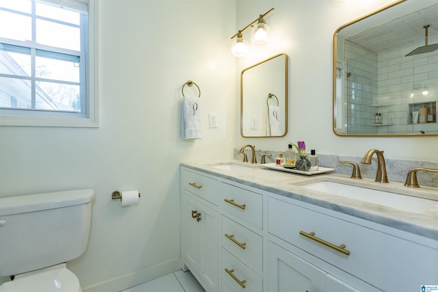 bathroom featuring double vanity, toilet, baseboards, and a sink