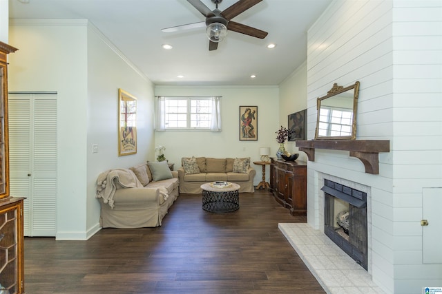 living area with wood finished floors, a ceiling fan, recessed lighting, a tiled fireplace, and crown molding