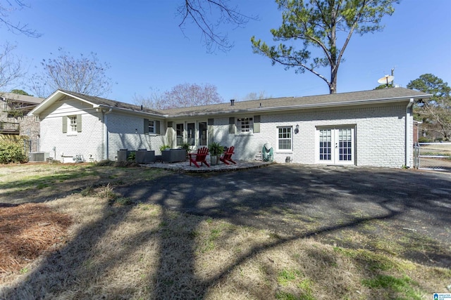 rear view of house with brick siding, a patio area, french doors, and central AC