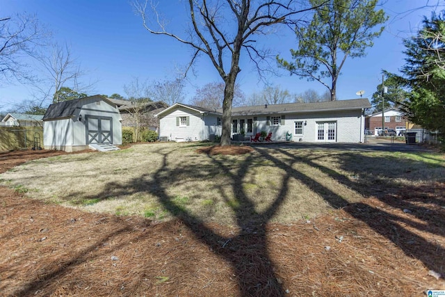 view of front facade featuring fence, a shed, a front yard, french doors, and an outbuilding