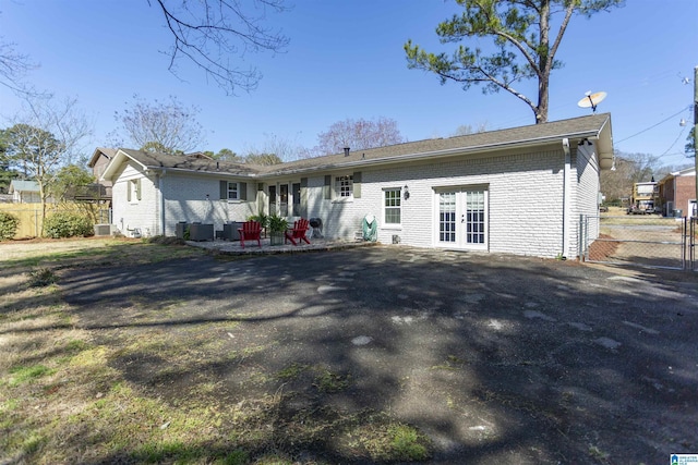 back of house with brick siding, french doors, a patio, and fence