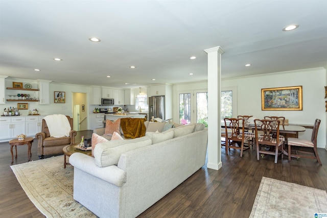 living area with decorative columns, recessed lighting, dark wood-style flooring, and ornamental molding