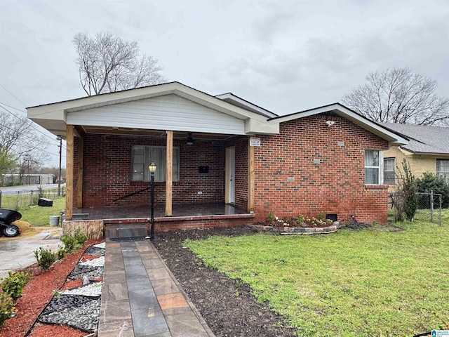 view of front facade with brick siding, covered porch, a front yard, and fence